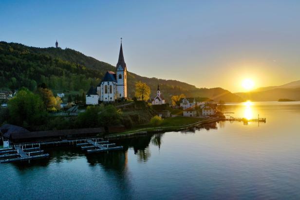 Die Pfarrkirche Maria Wörth am Wörthersee im goldenen Licht der Abendsonne.