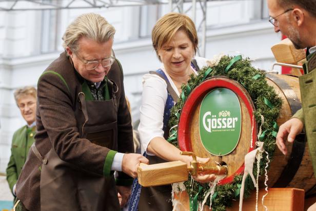 Eine Frau und ein Mann zapfen ein Bierfass der Marke Gösser an.