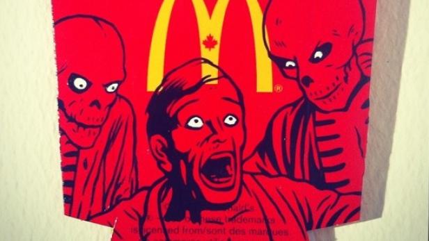 Ein Mann schreit entsetzt zwischen zwei skelettartigen Figuren vor einem McDonald's-Logo.