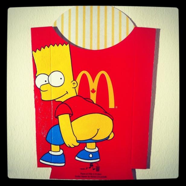 Bart Simpson hockt vor einer roten McDonald's-Pommes-Verpackung.