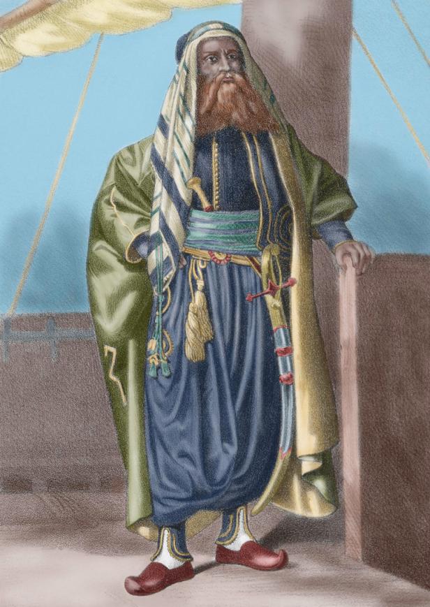 Ein Mann mit Bart trägt traditionelle Kleidung und einen Turban.