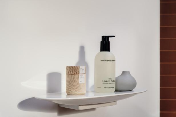 Eine Flasche Handseife, ein Holzkästchen und eine kleine Vase auf einem Regal.