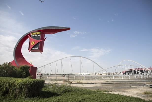 Ein Schild für Ferrari World in Abu Dhabi vor einer Achterbahn.
