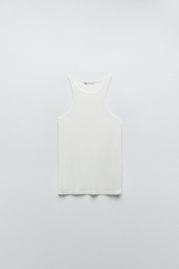 Ein weißes Tanktop liegt auf einem weißen Hintergrund.