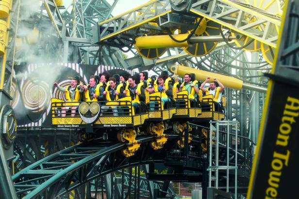 Menschen fahren mit einer gelben Achterbahn im Alton Towers Resort.