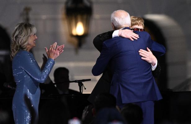 Jill Biden klatscht, während Joe Biden Elton John umarmt.