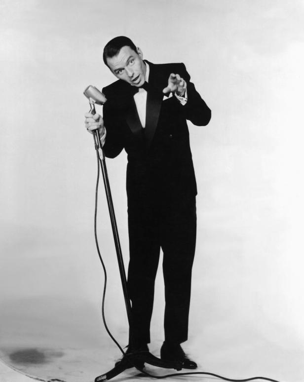 Frank Sinatra singt in einem Smoking vor einem Mikrofon.