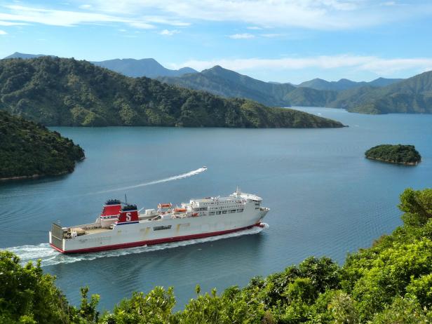 Eine Fähre fährt durch eine malerische Wasserstraße mit bewaldeten Hügeln.