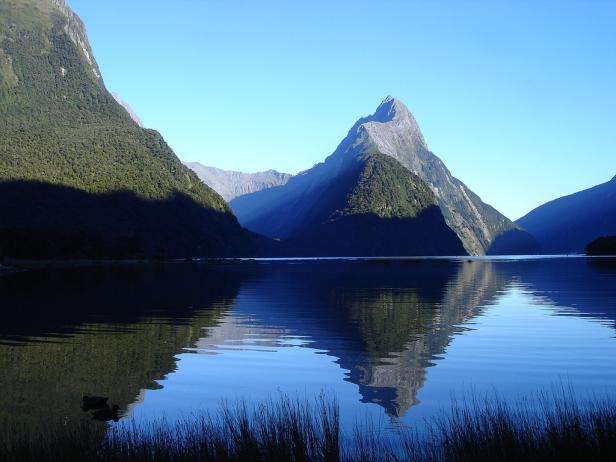 Der Mitre Peak spiegelt sich im ruhigen Wasser des Milford Sound, Neuseeland.