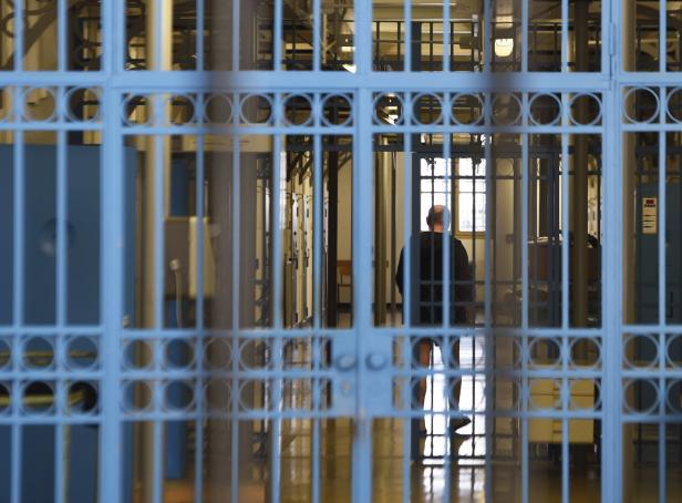 Ein Mann steht hinter Gittern im Gefängnis