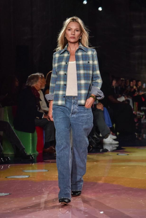 Kate Moss läuft in Jeans und einem karierten Hemd auf einem Laufsteg.