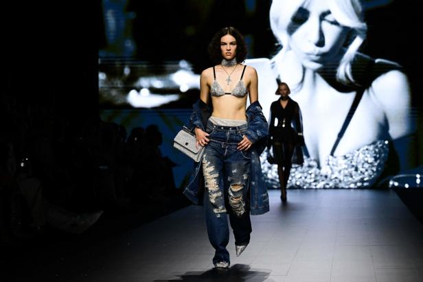 Eine Frau in zerrissenen Jeans und einem glitzernden BH auf einem Laufsteg.