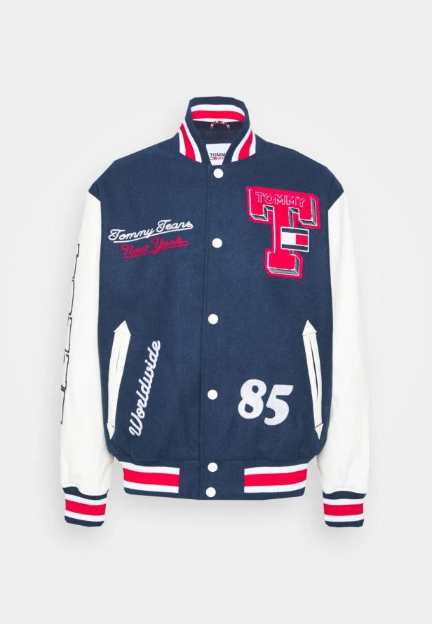 Eine blaue Tommy Jeans Collegejacke mit weißen Ärmeln und roten Akzenten.