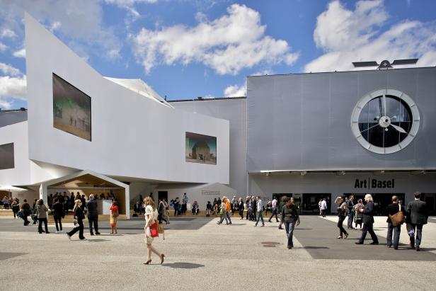 Besucher strömen zur Kunstmesse Art Basel vor einem modernen Gebäude.