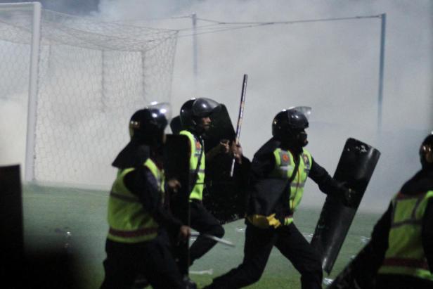 Riot police officers get into action during a riot after the league BRI Liga 1 football match between Arema vs Persebaya at Kanjuruhan Stadium in Malang