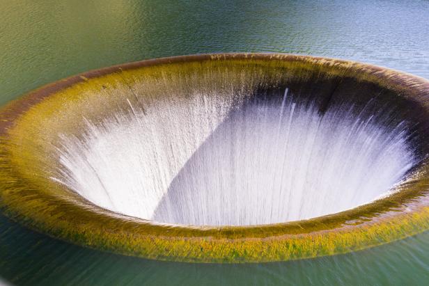 Wasser fließt in ein großes, kreisförmiges Überlaufbecken.