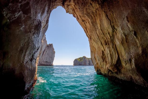 Blick aus einer Grotte auf das türkisblaue Meer und Felseninseln.