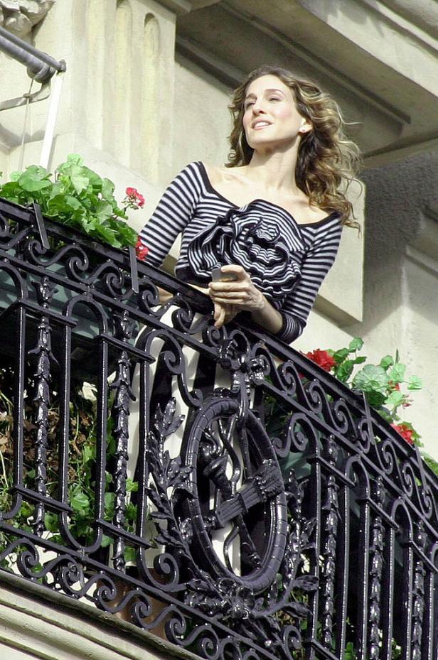 Sarah Jessica Parker steht auf einem Balkon mit Blumenkästen.