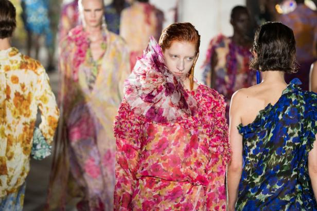Models präsentieren florale Designs auf einem Laufsteg.