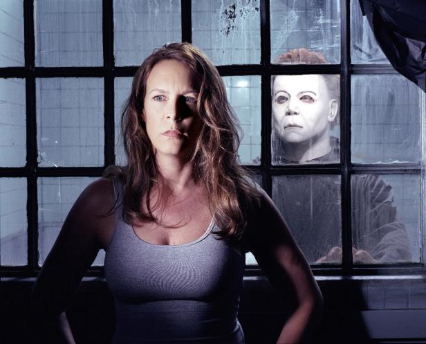 Jamie Lee Curtis steht vor einem Fenster, hinter dem Michael Myers zu sehen ist.