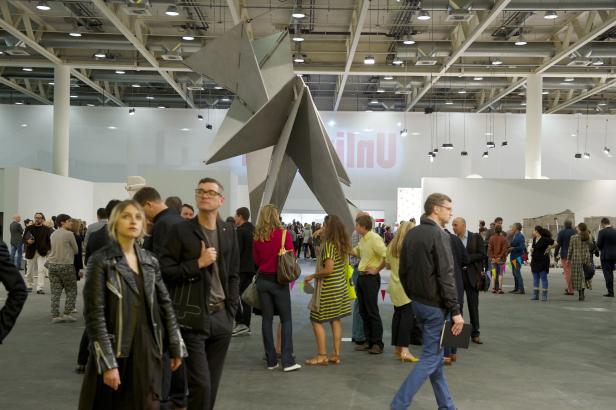 Besucher betrachten eine große, abstrakte Skulptur in einer Ausstellungshalle.