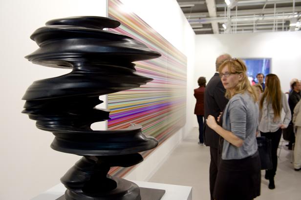Besucher betrachten eine abstrakte, schwarze Skulptur in einer Kunstgalerie.