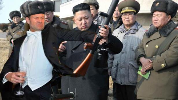 Kim Jong-un inspiziert eine Waffe, während ein Mann im Smoking ein Glas hält.