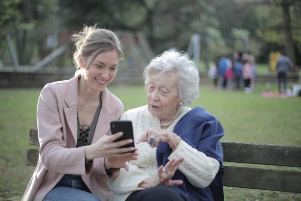 Junge Frau zeigt älterer Dame etwas auf dem Handy