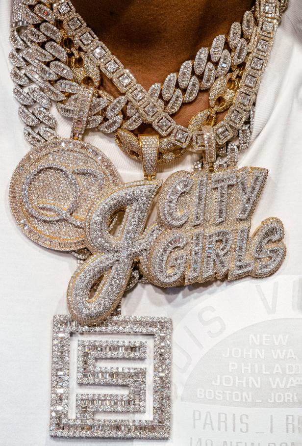 Nahaufnahme von mehreren goldenen und silbernen Diamantketten mit Anhängern, darunter „City Girls“.