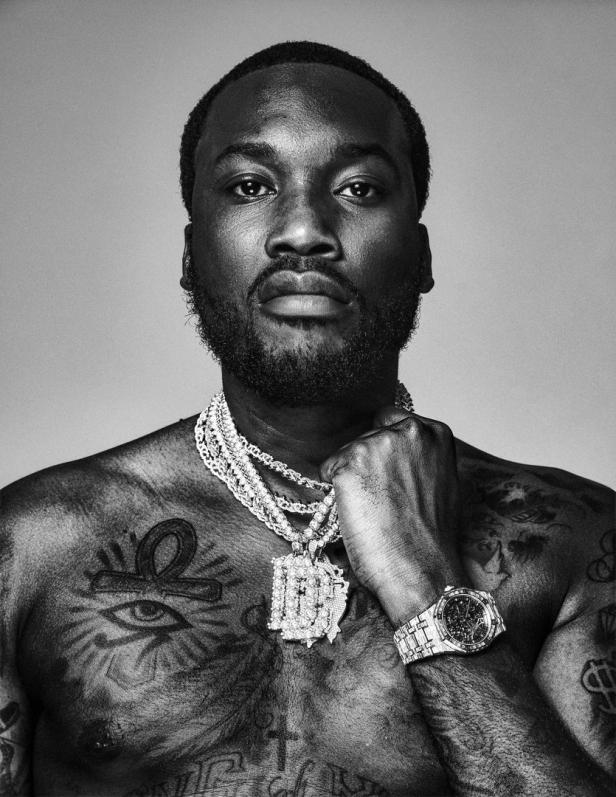 Ein Schwarz-Weiß-Porträt von Meek Mill mit Tätowierungen und Schmuck.