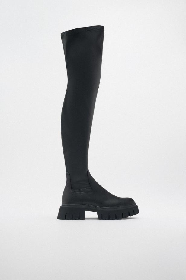 Ein schwarzer Overknee-Stiefel mit dicker Profilsohle vor einem weißen Hintergrund.