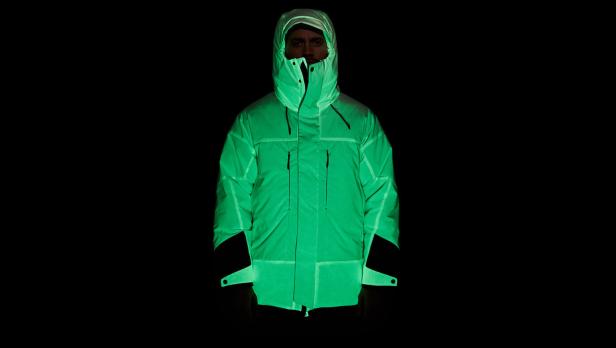 Eine Person trägt eine leuchtend grüne Jacke mit Kapuze im Dunkeln.