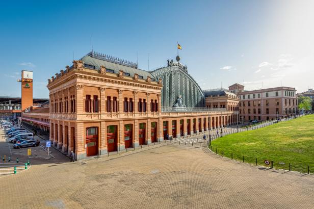 Die Fassade des Bahnhofs Atocha in Madrid unter blauem Himmel.