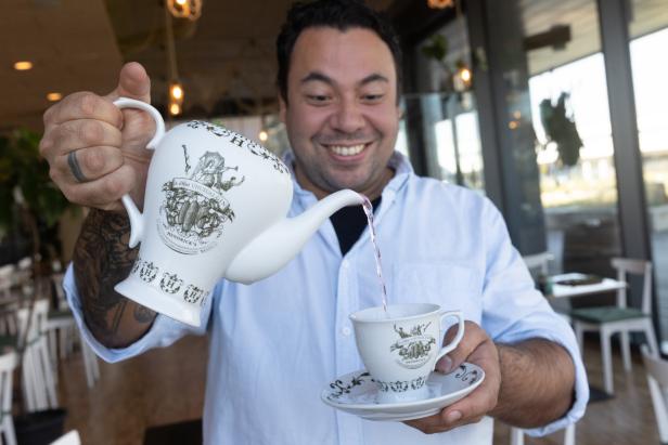 Ein Mann gießt Tee aus einer Hendrick's Teekanne in eine Tasse.