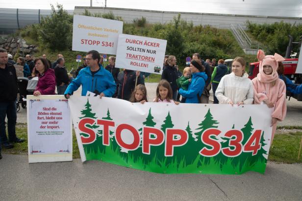 Demonstrierende mit Protestplakaten gegen die S34 und für den Ausbau des öffentlichen Verkehrs, einige Kinder vorn.
