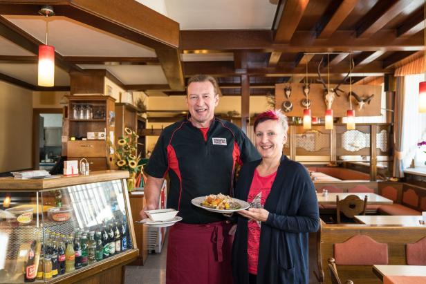 Ein Mann und eine Frau vom Gasthof Hutter präsentieren Speisen.