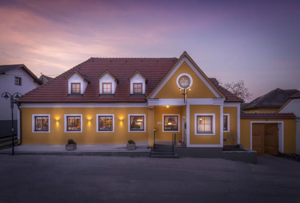 Ein gelbes Haus mit roten Ziegeln unter einem violetten Himmel in der Abenddämmerung.