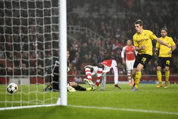 Ein Fußballspieler von Arsenal fällt im Strafraum, während ein Dortmunder Spieler zusieht.