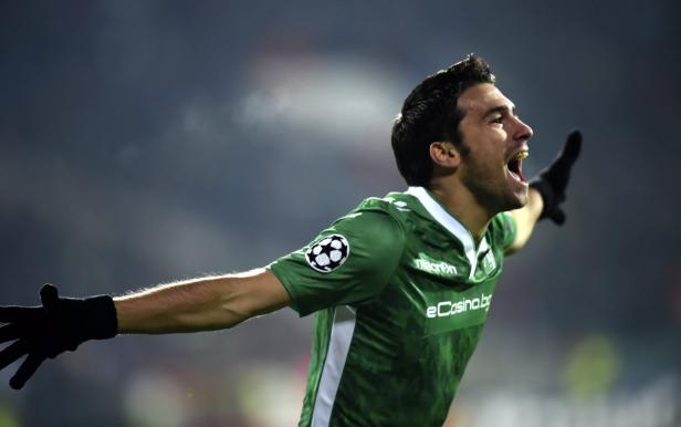 Ein Fußballspieler in Grün jubelt mit erhobenen Armen.