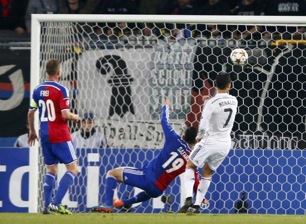 Cristiano Ronaldo schießt den Ball ins Tor, während ein Verteidiger zu verhindern versucht.