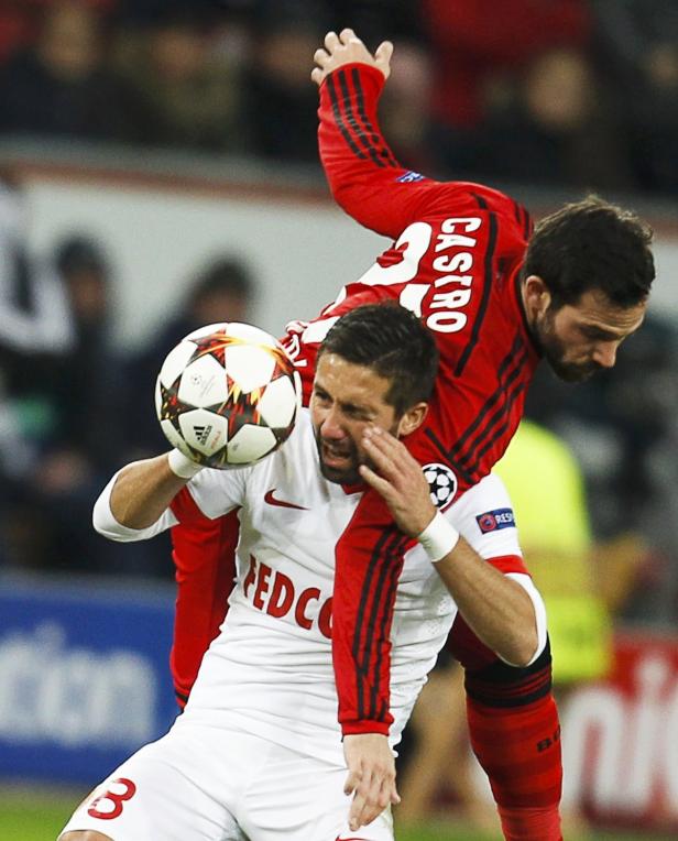 Ein Fußballspieler in Weiß wird von einem Spieler in Rot während eines Spiels behindert.