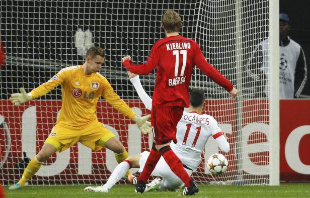Ein Fußballspiel mit einem Torwart in Gelb und zwei Spielern vor dem Tor.