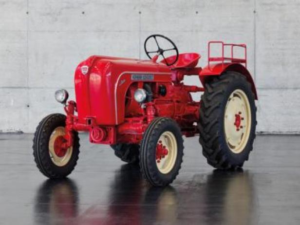 Ein roter Porsche Diesel Traktor steht vor einer grauen Wand.