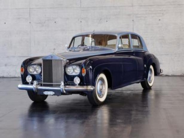 Ein dunkelblaues Rolls-Royce-Oldtimermodell mit silbernem Dach steht in einem Ausstellungsraum.