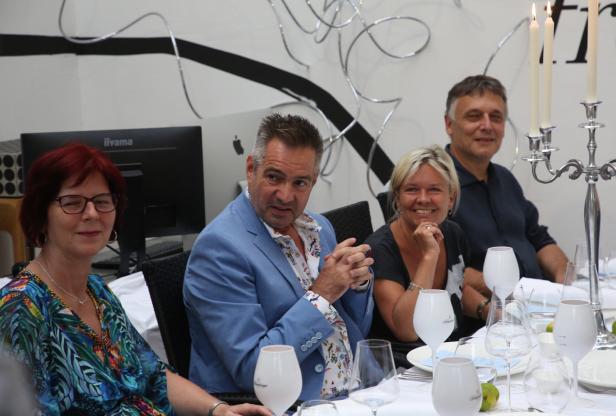 Eine Gruppe von vier Personen sitzt an einem gedeckten Tisch bei einer Feierlichkeit.