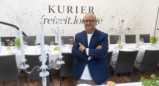 Ein Mann in einem blauen Sakko steht vor einem gedeckten Tisch der „Kurier Freizeit.Lounge“.