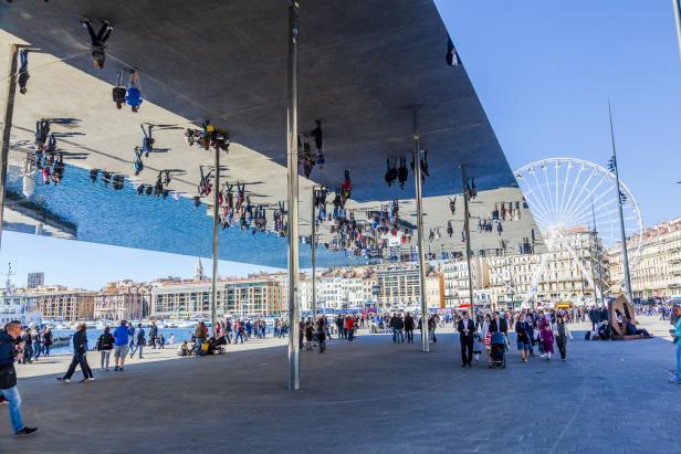 Das Spiegelzelt am Hafen von Marseille reflektiert Menschen und das Stadtbild.