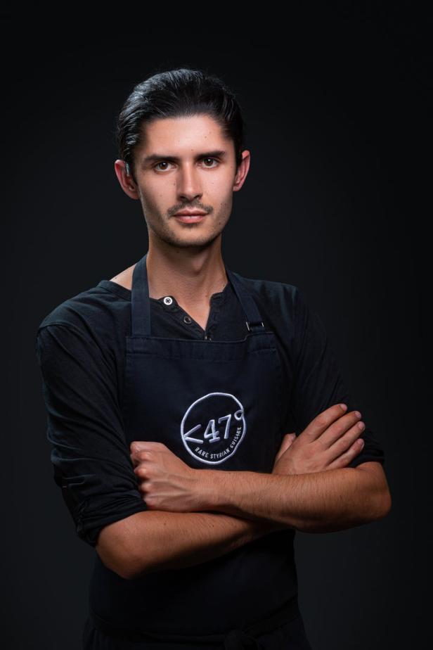 Ein Mann mit verschränkten Armen, bekleidet mit einer Kochschürze des Restaurants „47° Rare Styrian Cuisine“.