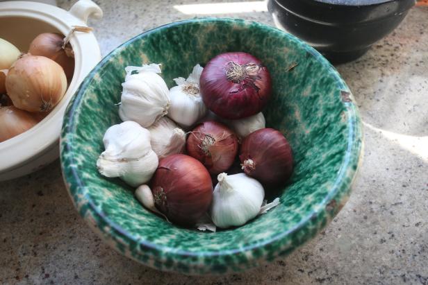 Eine grüne Schüssel ist gefüllt mit roten Zwiebeln und Knoblauch.