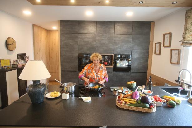 Eine Frau kocht in einer modernen Küche mit frischem Gemüse.